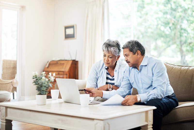 What Do Air Purifiers and Air Filters Do? Shot of a senior couple using a laptop together at home, sitting on a couch in their living room.